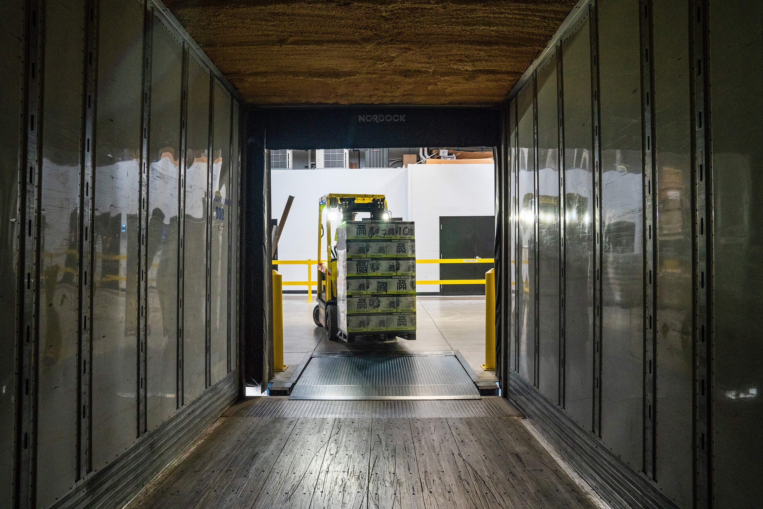 Forklift with boxes stacked driving into storage container